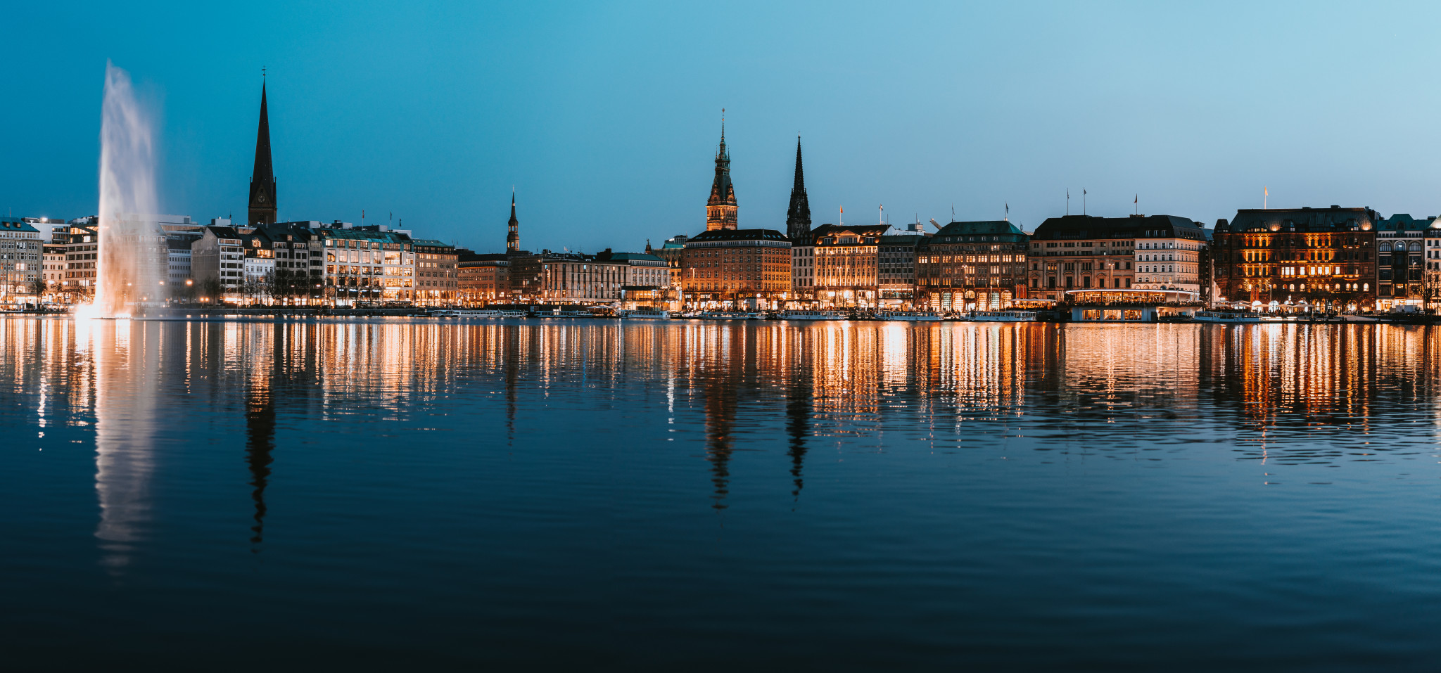 beautiful panoramic view of hamburg town hall rathaus and alster river at spring earning evening during blue hour